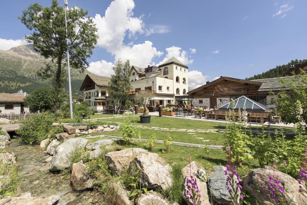 a large building with a yard with rocks and flowers at Hotel Bellavista in Silvaplana