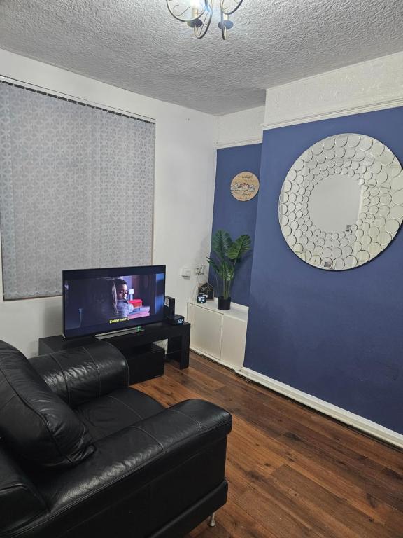 a living room with a couch and a flat screen tv at Your Happy Place-2 Bedroom House in Liverpool