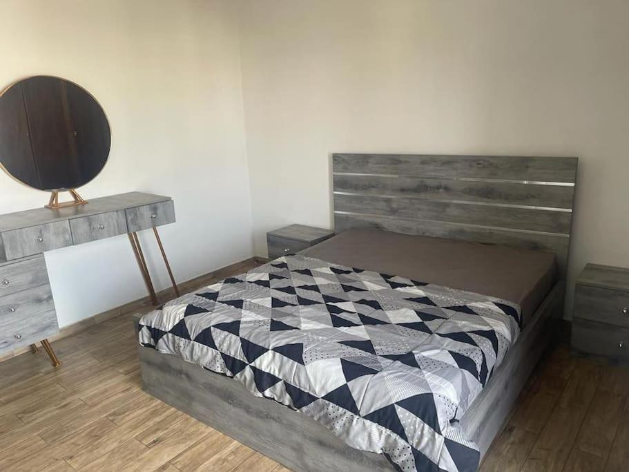 Schlafzimmer mit einem Bett mit einem Kopfteil aus Holz und einem Tisch in der Unterkunft Spacieux F4 confort et modernité in Dakar