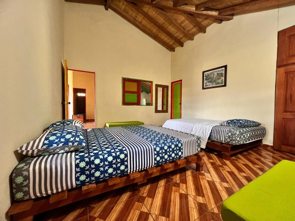 2 camas en una habitación con suelo de madera en RESIDENCIA ARTISTICA Y HOSTAL LOS COLORES, en Jericó