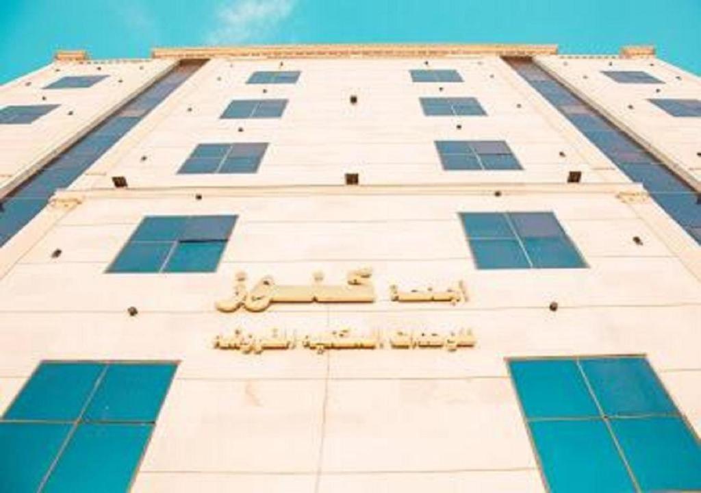 a tall white building with blue windows at اجنحة كنوز in Jeddah