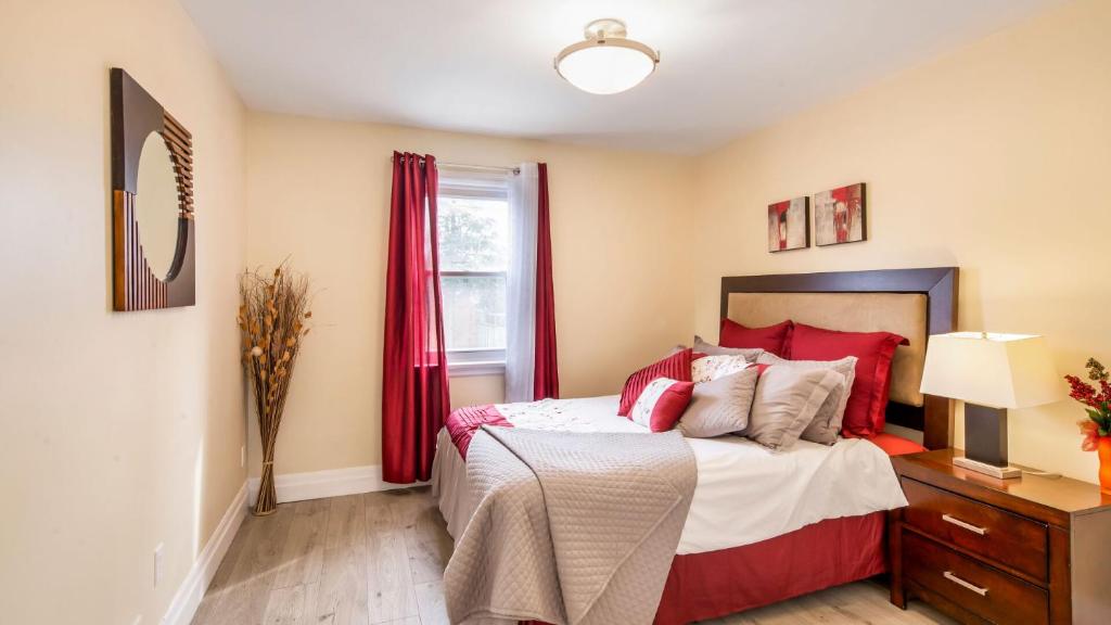 um quarto com uma cama com almofadas vermelhas e uma janela em 2 Bedroom East-York bungalow em Toronto