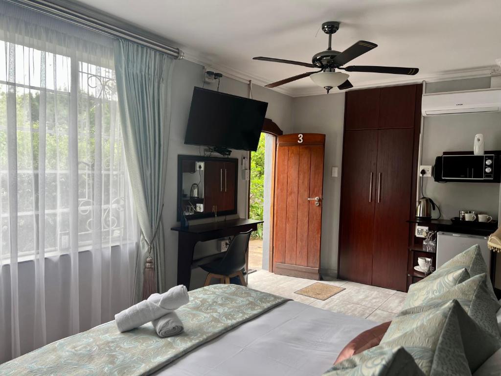 Schlafzimmer mit einem Bett, einem Deckenventilator und einem Fenster in der Unterkunft Silken Trap Accommodation NO LOADSHEDDING in Johannesburg
