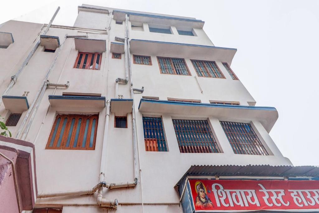een hoog wit gebouw met ramen en een bord erop bij OYO Shivaye Rest House in Deoghar