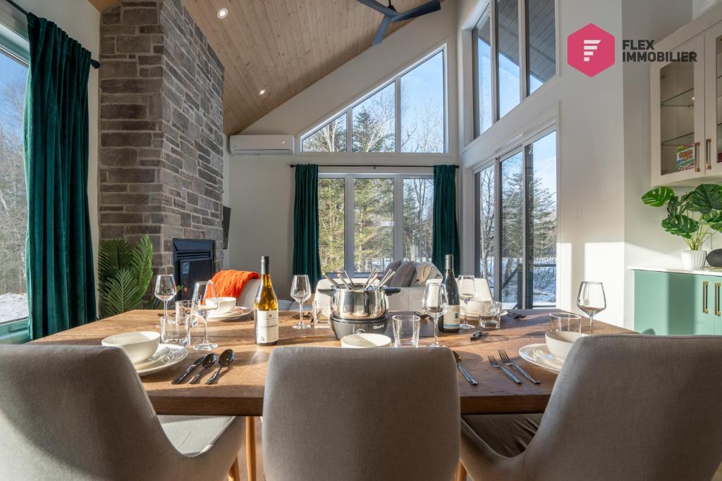 a dining room with a long wooden table and chairs at The Green Chill at Cité-Jardin - Private SPA, Ping pong, Fireplace & Pool in Saint-Basile