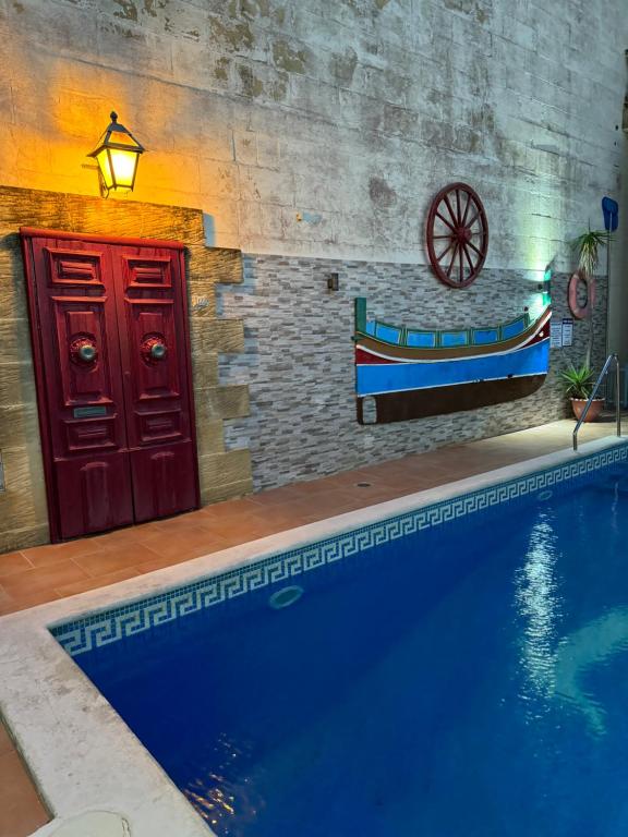 a swimming pool in front of a building with a boat on the wall at Tal-Bir Farmhouse in Nadur