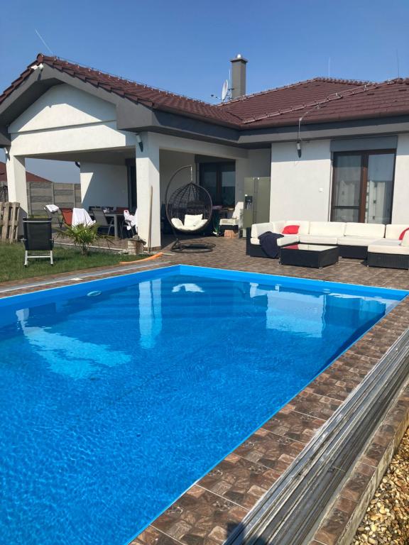 a blue swimming pool in front of a house at Dom s bazénom a záhradou na dovolenku snov in Topoľníky
