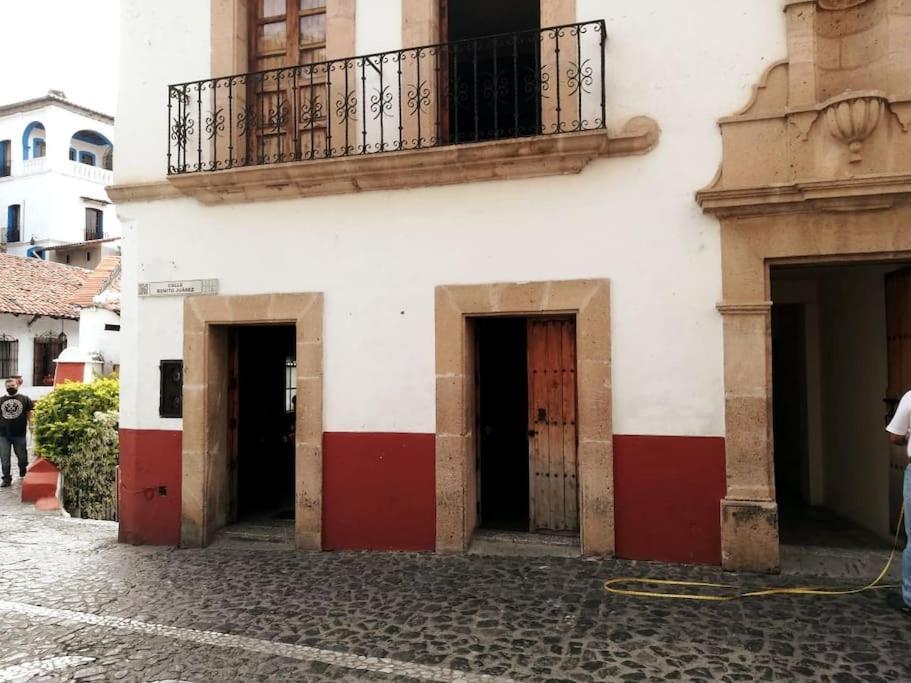 a building with three doors and a balcony on it at La cabaña del TIO PEPE in Taxco de Alarcón