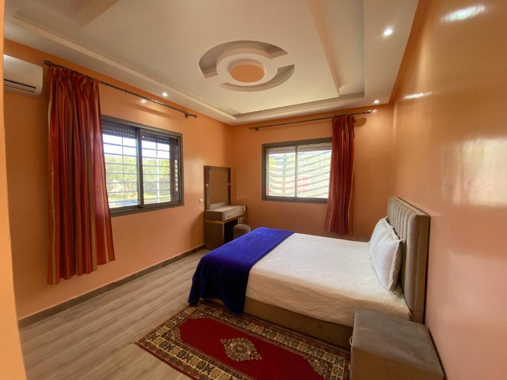 馬拉喀什的住宿－Villa famille Bilal Agafay，一间卧室设有一张床和两个窗户。