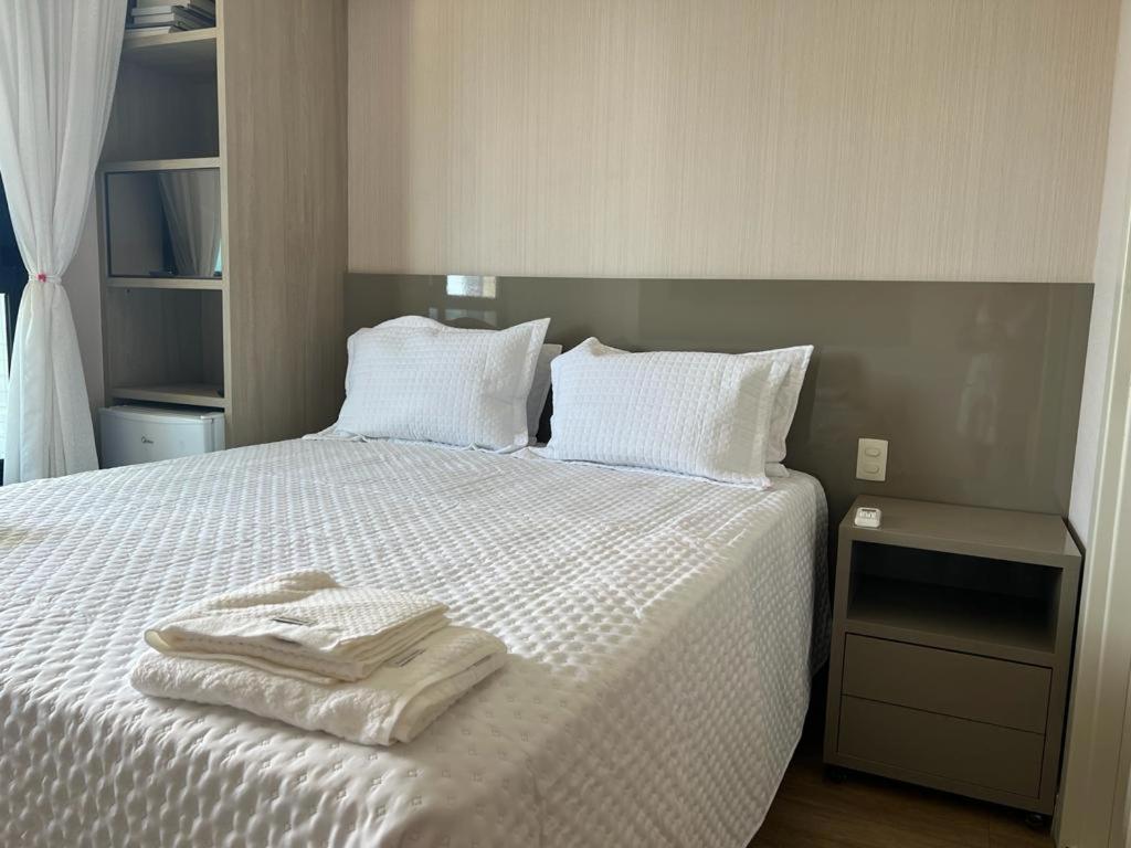 - un lit avec des draps et des oreillers blancs dans l'établissement Suíte Apart Hotel Mondial Salvador, à Salvador