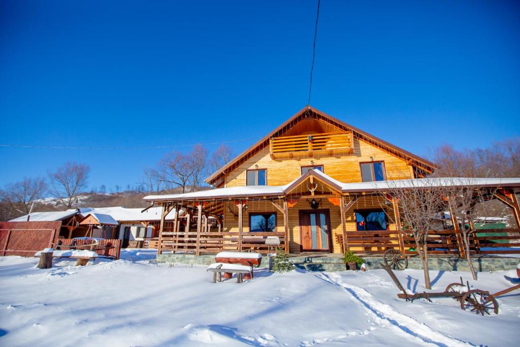 a log cabin in the snow with snow covered yard at Cabana Lunca in Tîrgu Neamţ