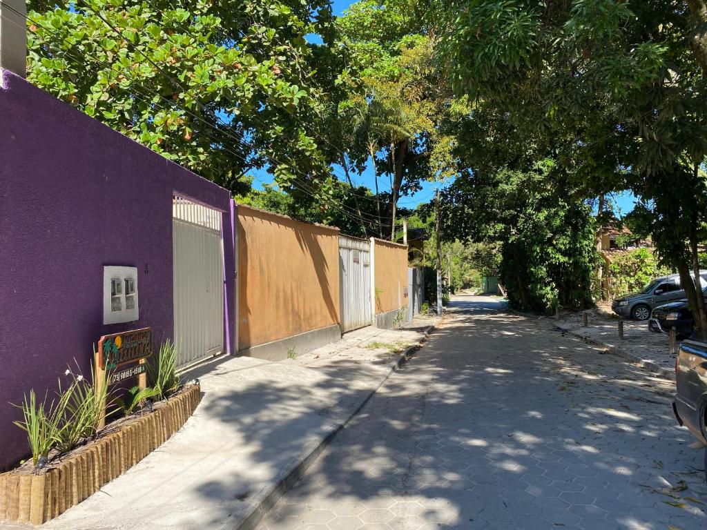 una calle vacía con un edificio púrpura y árboles en Apartamentos Terra Mar, en Trancoso