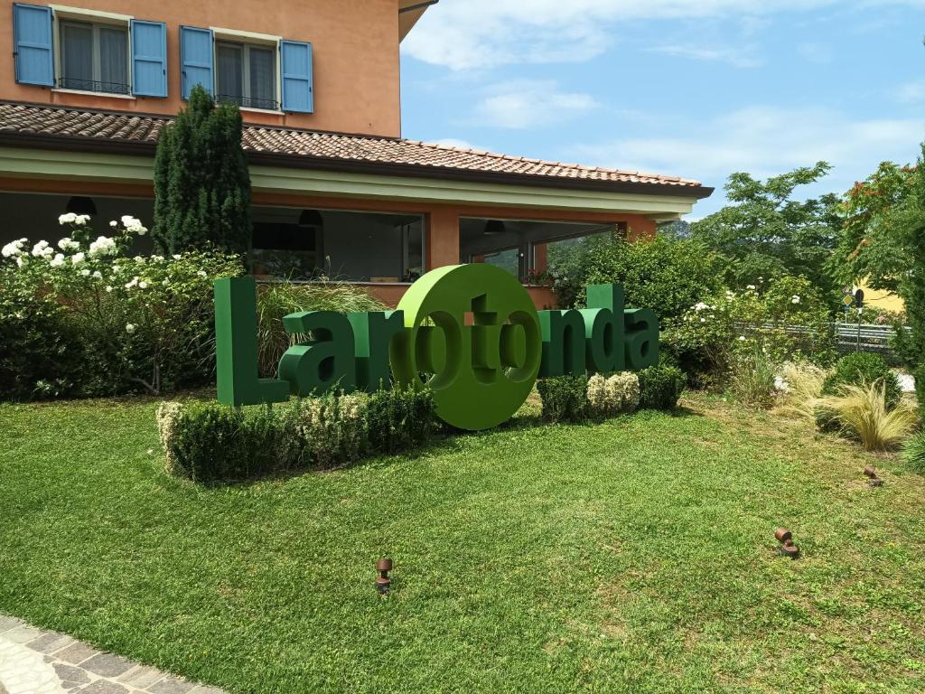 a house with a green sign in front of a yard at Locanda LaRotonda in Villa Verucchio