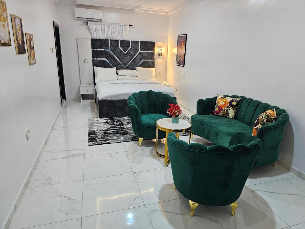 1 dormitorio con 2 sillas verdes y 1 cama en Extreme Royal Hotel and Suites, en Lagos