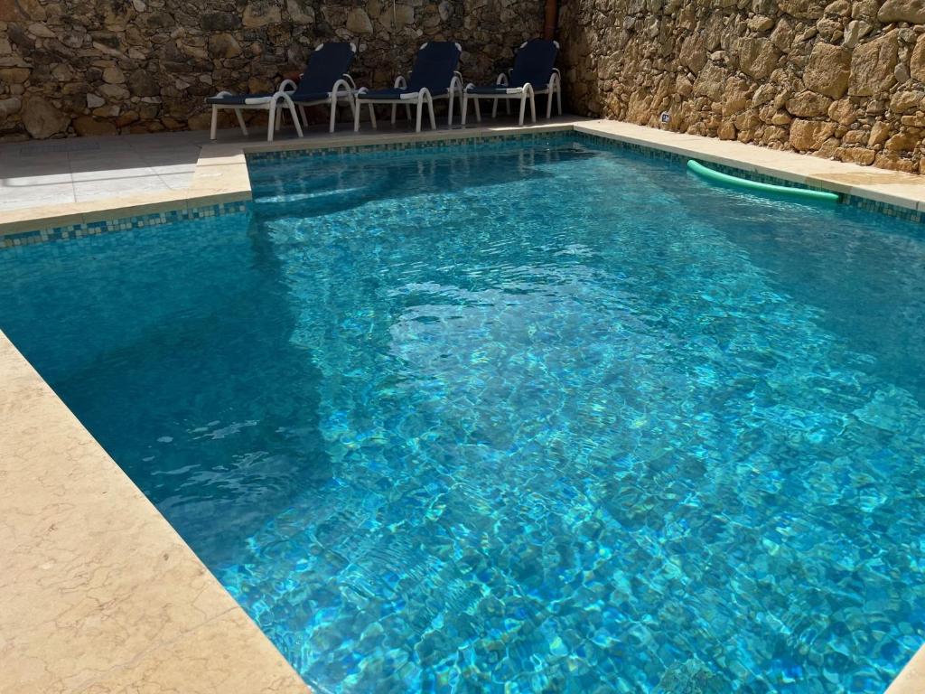 a large blue swimming pool with chairs in it at 4 Bedroom Holiday Home with Private Pool & Views in Xewkija