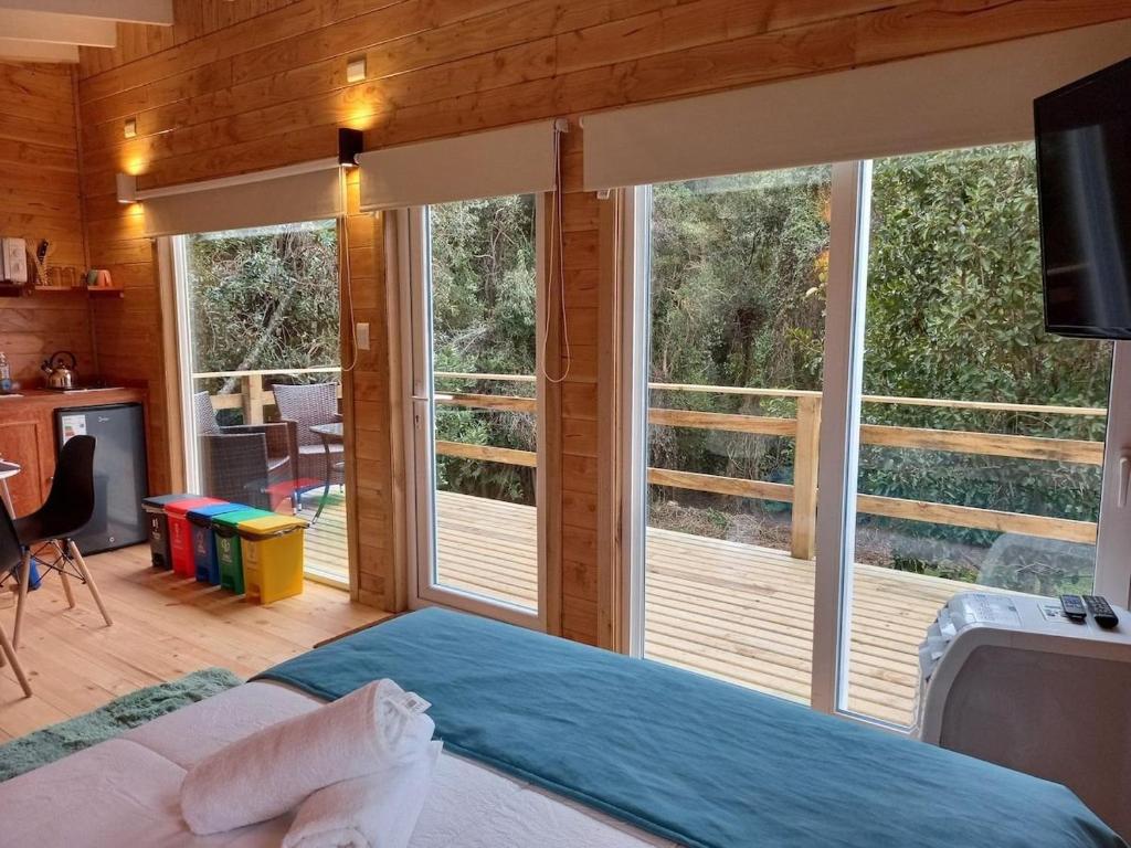 ein Schlafzimmer mit einem Bett und einem großen Fenster in der Unterkunft Tiny House con opción de tina temperada in Puerto Varas