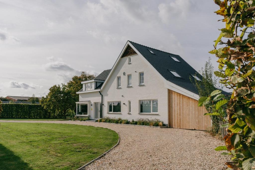 una casa blanca con techo negro en MAM Haspengouw en Sint-Truiden