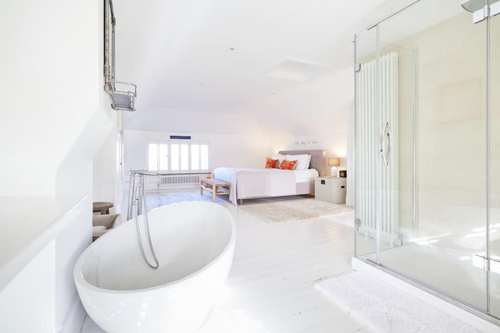 a white bathroom with a tub and a bedroom at The Sea House Beautiful Large Whitstable Home With Sea Views in Kent