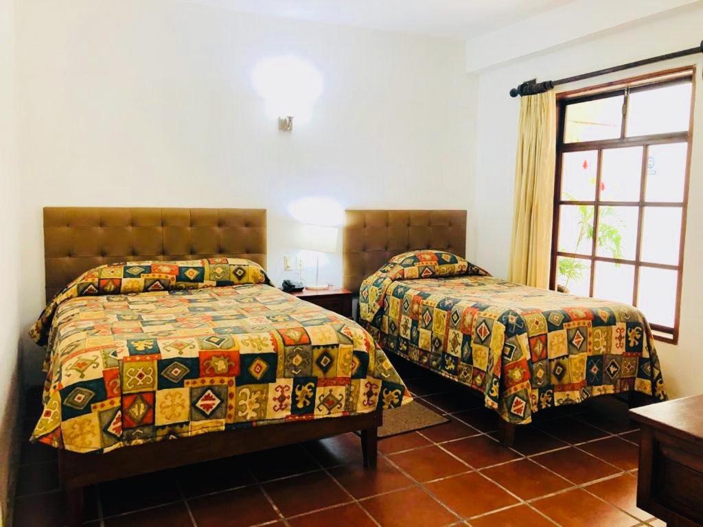 1 dormitorio con 2 camas y ventana en posada el castellano, en Comitán de Domínguez