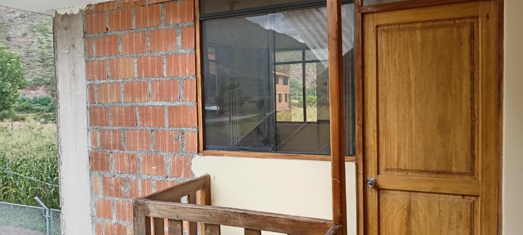 a brick wall with a window and a wooden door at Casa de George in Urubamba