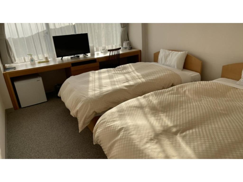 two beds in a room with a desk and a television at Shonan Relief - Vacation STAY 50852v in Yokosuka