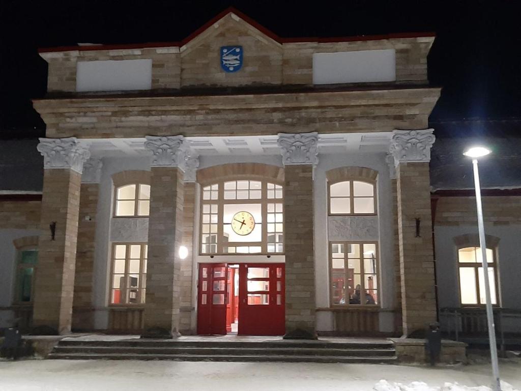 un gran edificio de piedra con una puerta roja por la noche en Rooms near the station, en Narva