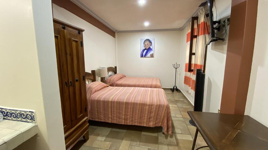 a hotel room with two beds and a table at Posada Regional in Oaxaca City