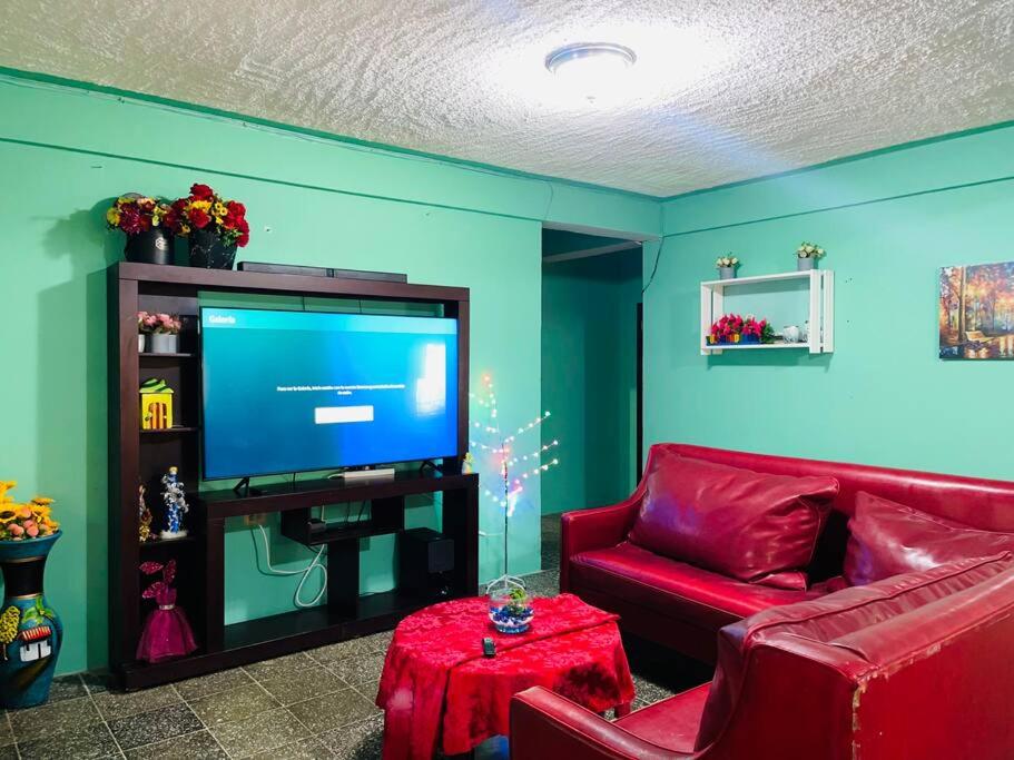 a living room with a red couch and a flat screen tv at Agradable casa de 4 habitaciones 2 baños cómodos in La Ceiba