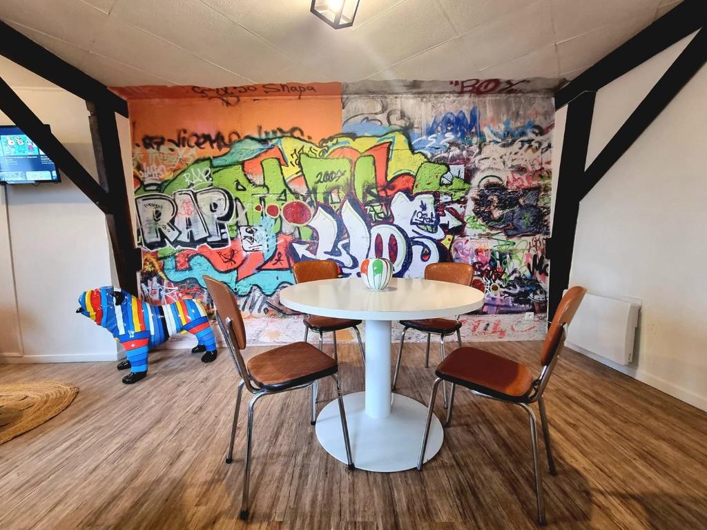 een tafel en stoelen voor een muur met graffiti bij L'Expo in Hénin-Beaumont