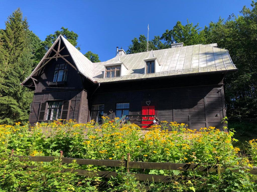 una casa con una puerta roja en un campo de flores en Dom Pracy Twórczej Muchomorek en Pieszyce