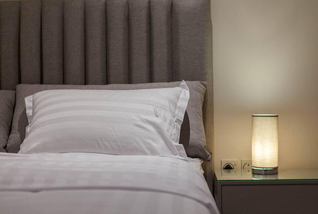 شقة انيقة وفاخرة بحي العليا Elegant and luxurious apartment Al-Olaya في الرياض: سرير مع وسادة بيضاء وطاولة مع مصباح