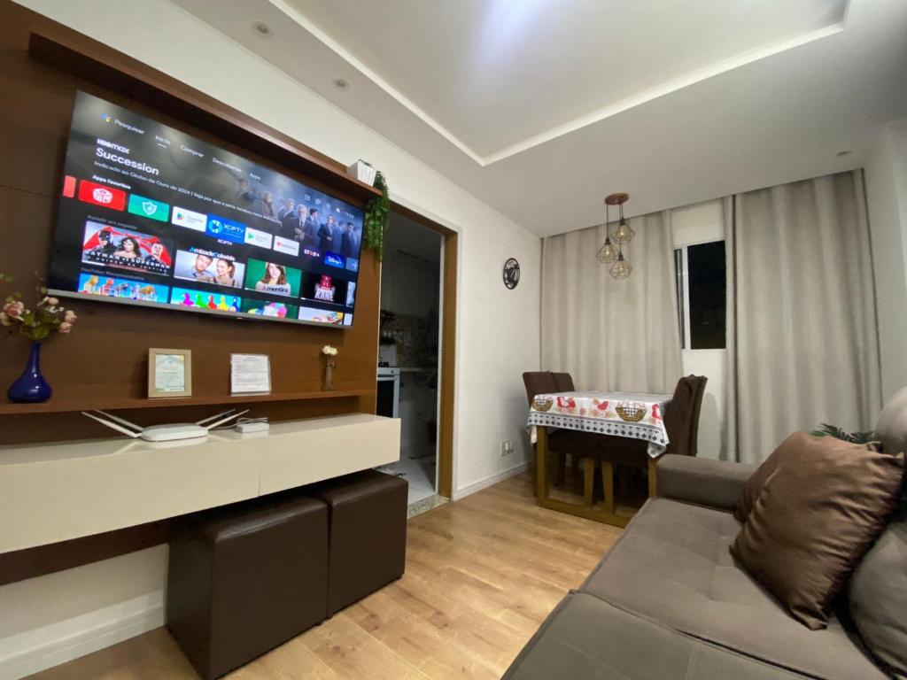 een woonkamer met een bank en een flatscreen-tv bij Apartamento 2 Quartos c/ Vaga de Estacionamento in Serra