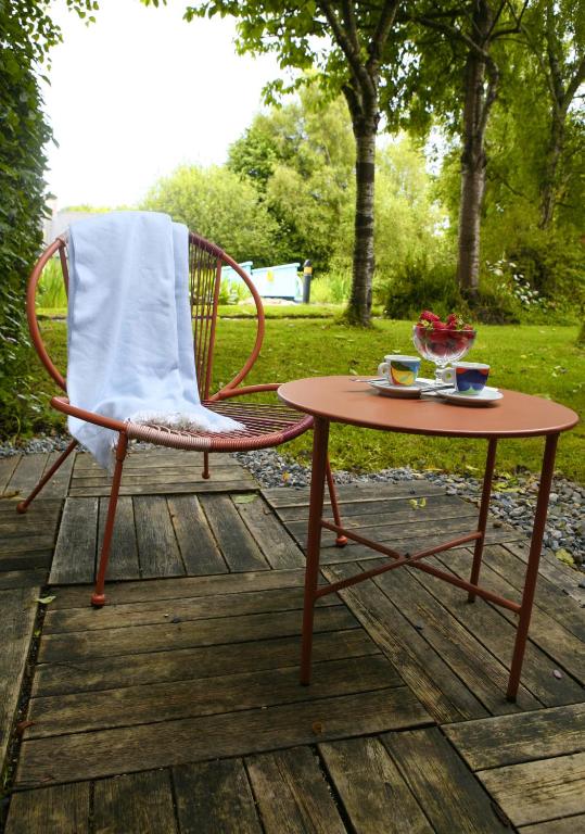 a chair and a table with a bowl of fruit on a deck at Blainroe Cottage in Blainroe