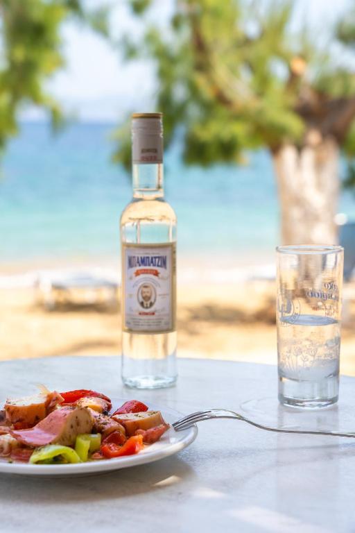 a bottle of alcohol next to a plate of food at Alexandros by the Beach - Serifos in Livadakia