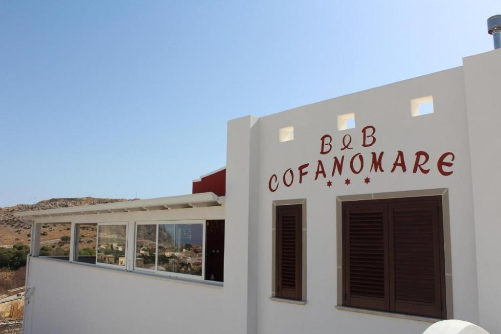 een wit gebouw met een bord waarop staat bc verzekering bij Cofanomare in Custonaci