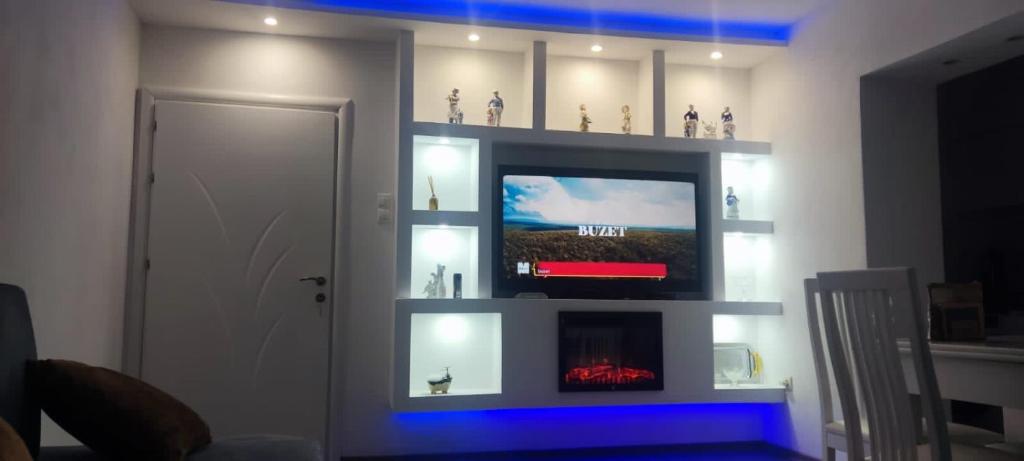 un soggiorno con TV e mensola con statuine di Ilia’s Guesthouse a Pogradec