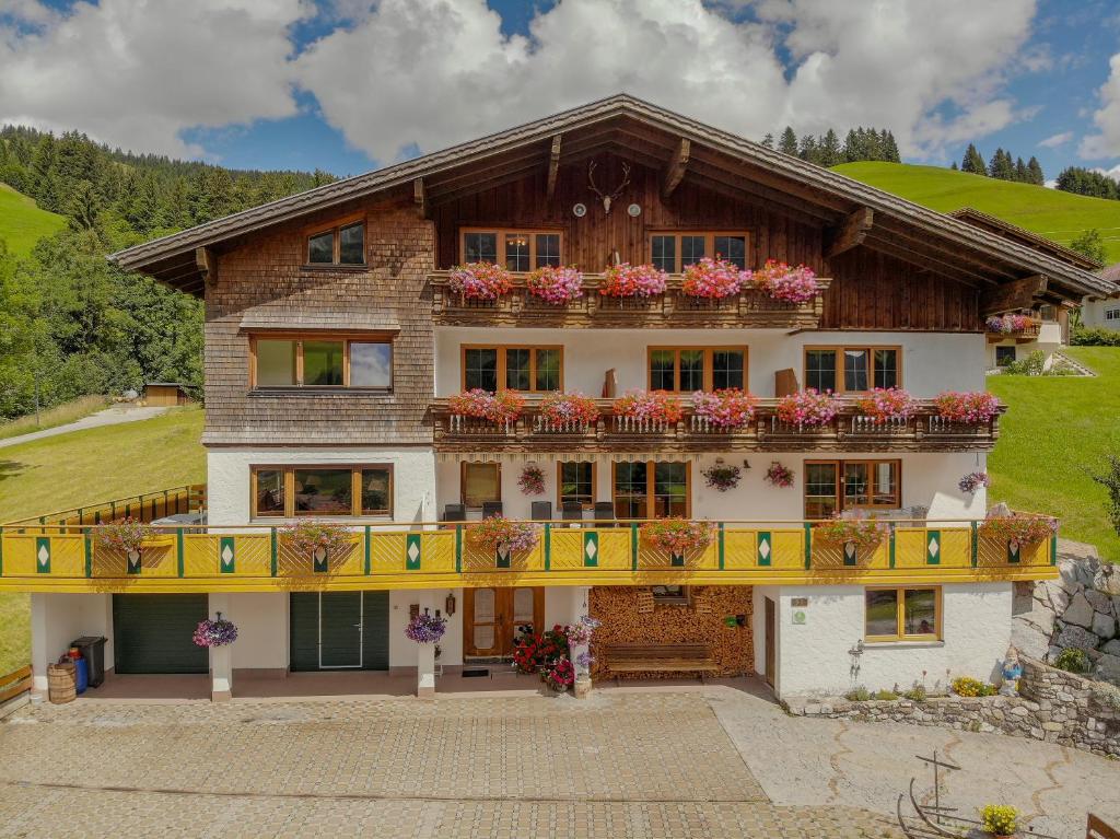 a house with flowers on the balconies of it at Gästehaus Almhof in Zöblen