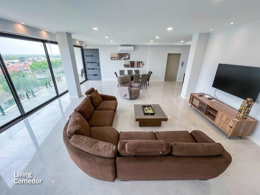sala de estar con sofá grande y TV en Departamento de lujo (240 metros cuadrados) 6to p en Santa Cruz de la Sierra