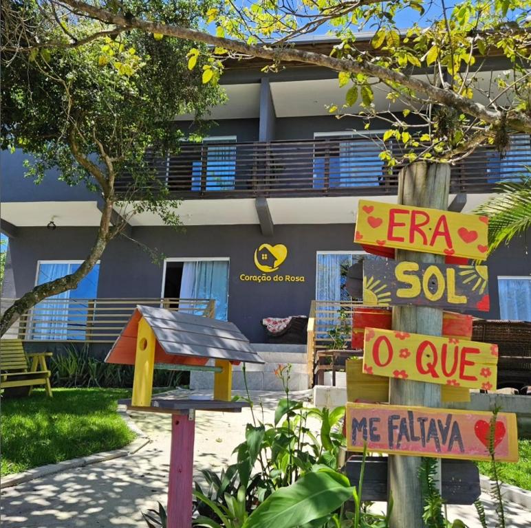 ein Schild vor einem Gebäude mit einem Haus in der Unterkunft Pousada Coração do Rosa in Praia do Rosa