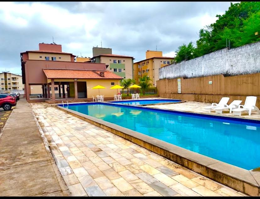 a swimming pool with chairs and umbrellas next to a building at APARTAMENTO CONFORTO in São Luís