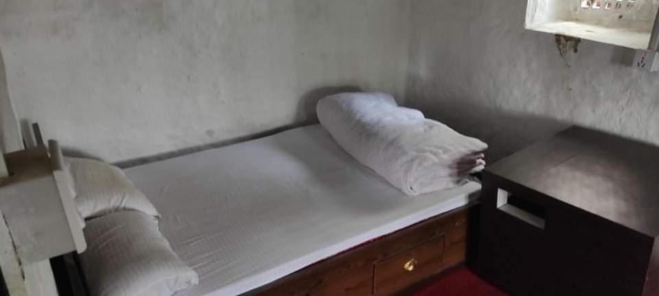 Bishramgriha في Dakshīnkāli: سرير في غرفة مع بطانيتين بيضاء