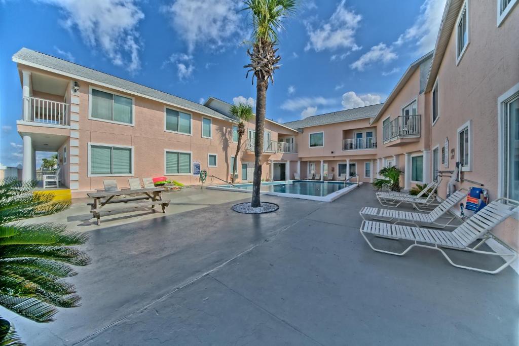 a courtyard with benches and a palm tree in front of a building at Pineapple Villas in Panama City Beach