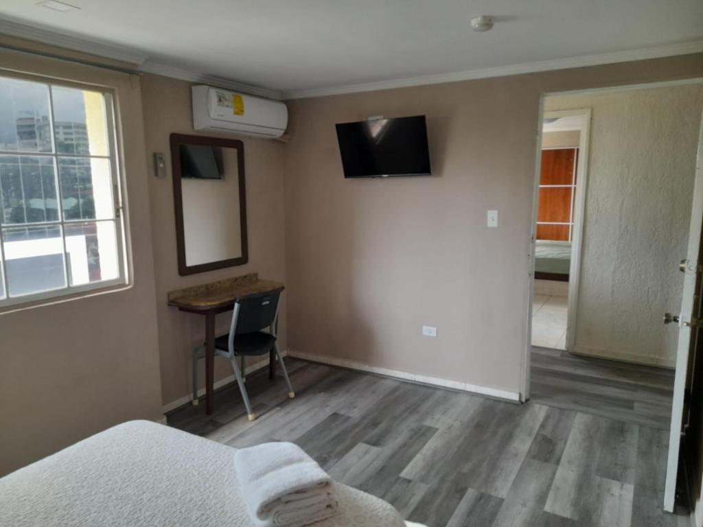 a room with a bed and a desk and a window at Hotel Dunas in Panama City