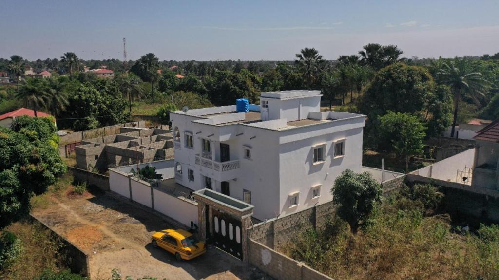 ein gelbes Auto, das vor einem weißen Haus parkt in der Unterkunft Jobz Luxury Rental - White Villa in Brufut