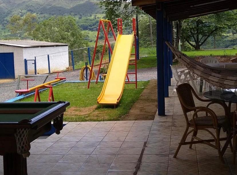 um parque infantil com uma mesa de bilhar e um escorrega em Sítio Cantinho da Cachoeira em Guapé