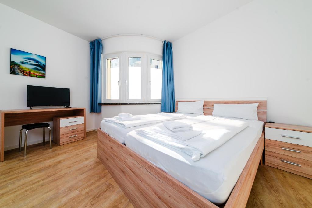 um quarto com uma cama grande e uma televisão em City Rooms Dortmund em Dortmund
