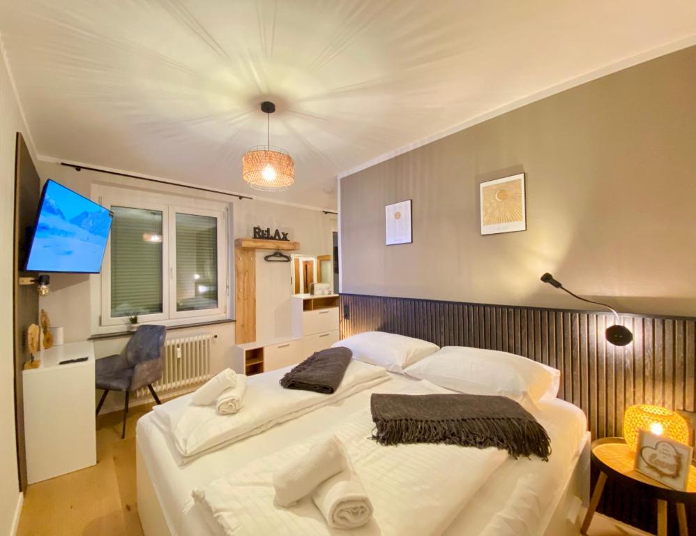 a bedroom with a large white bed and a tv at BaMo Studio - city living arkaden in Klagenfurt