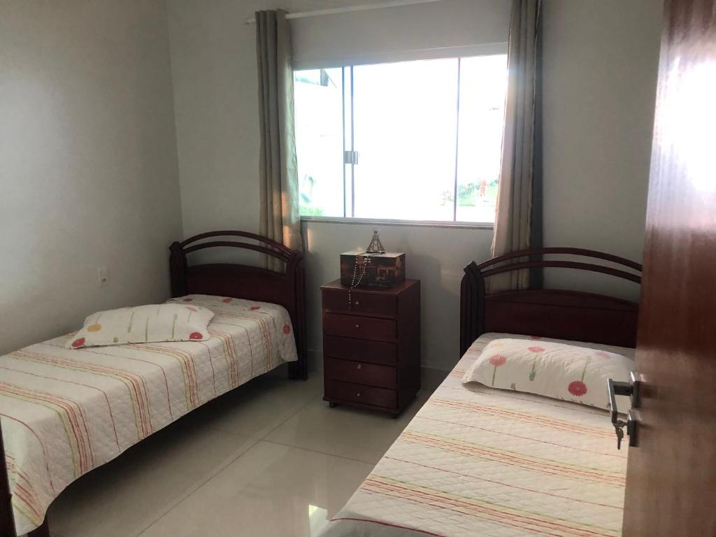 2 camas en una habitación pequeña con ventana en Suíte com janela para o jardim, en Goiânia