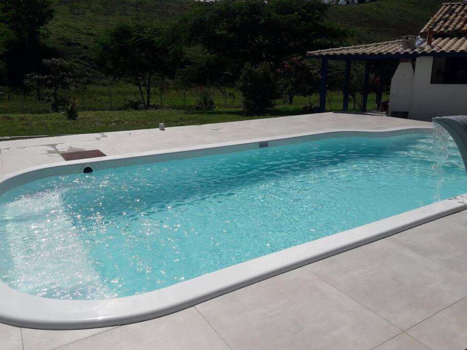 een groot zwembad met blauw water bij Sítio no interior de MG, lugar de sossego e paz! in São Domingos do Prata