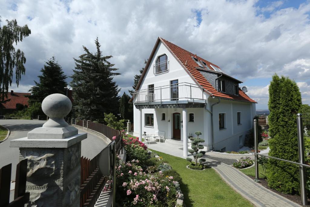 ein weißes Haus mit einem Zaun und Blumen in der Unterkunft Pension Clajus in Weimar